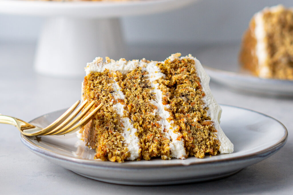 A slice of carrot cake laying on it's side on a small dessert plate.