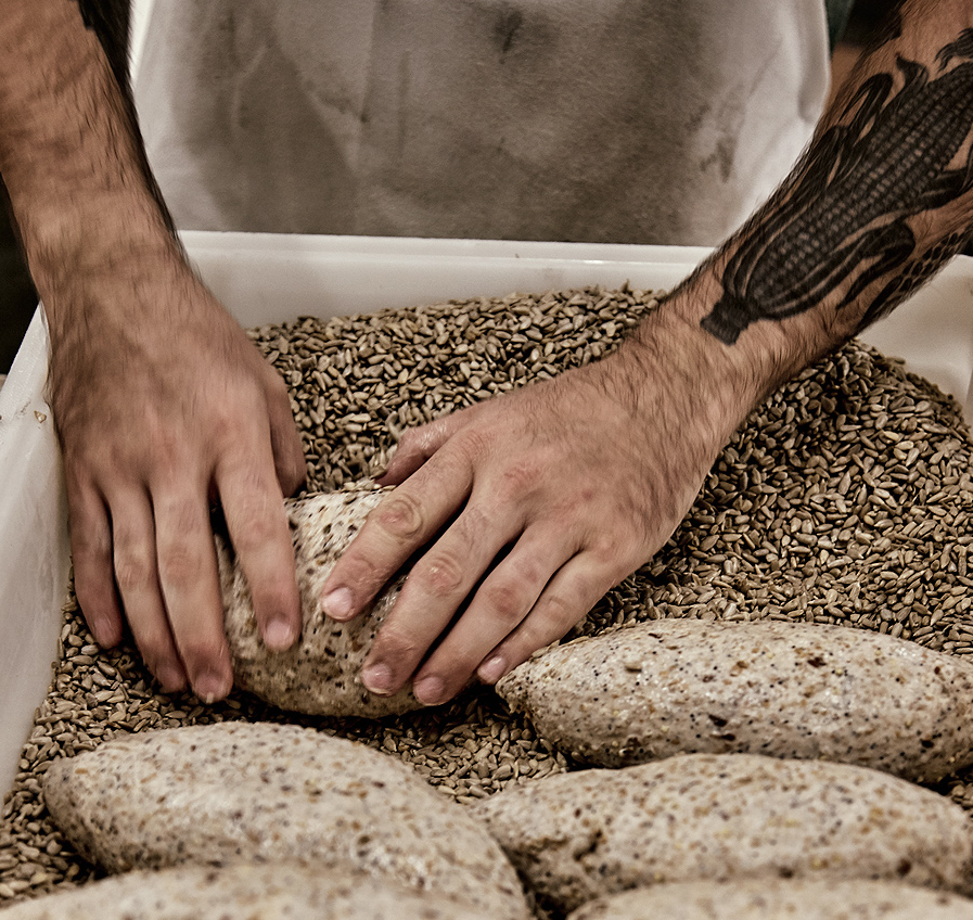 Hands rolling 8-grain 3-seed in sesame seeds