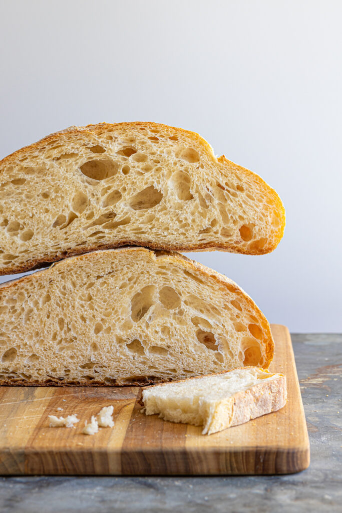 paesano bread loaf cut in half and stacked on a cutting board