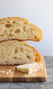 paesano bread loaf cut in half and stacked on a cutting board