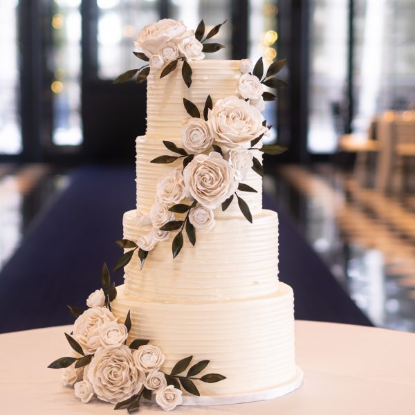 A 4-tiered white wedding cake covered in white gumpaste flowers